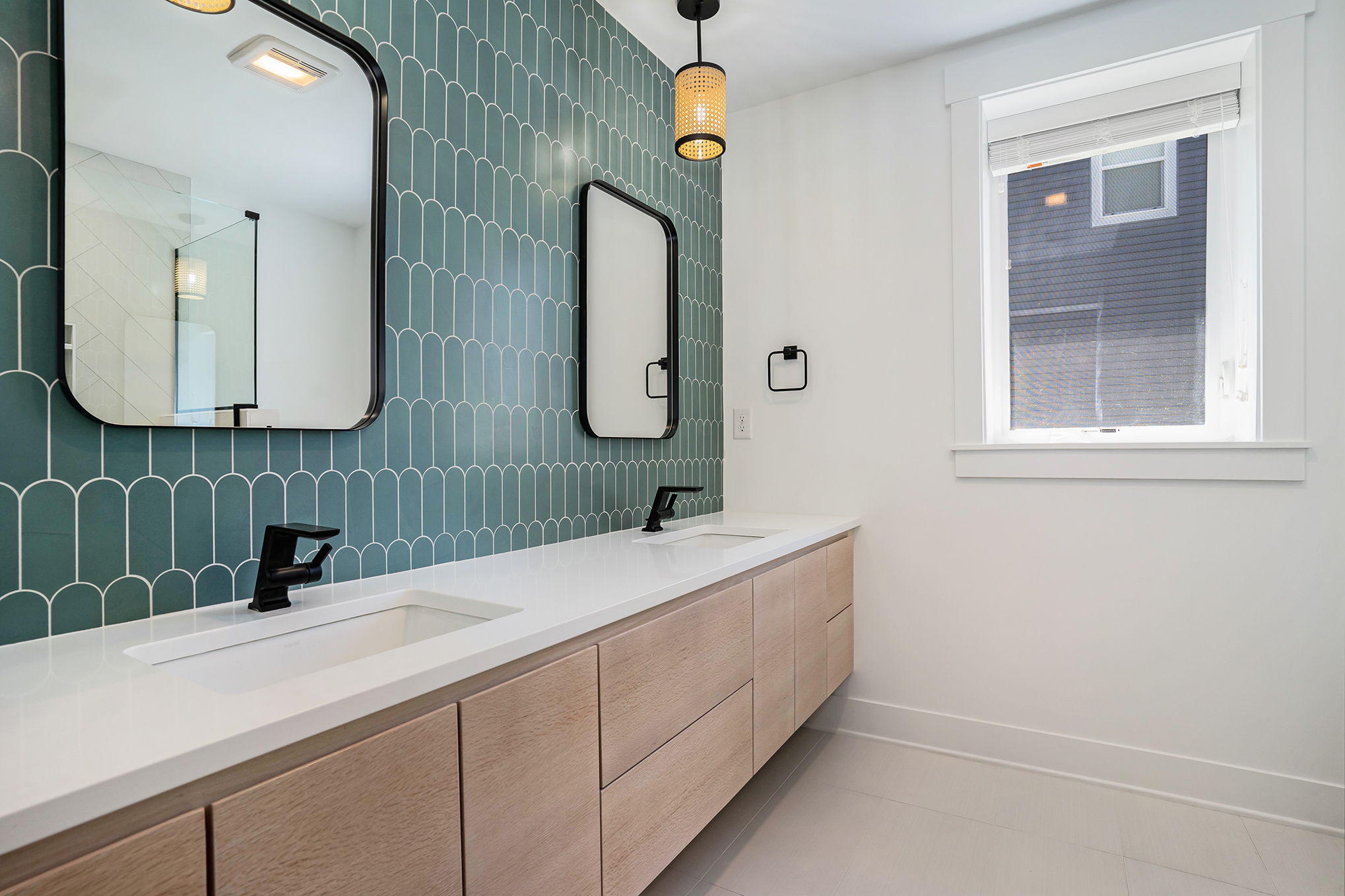 Remodeled bathroom with floating double vanity and teal tile backsplash, built by PR Design Build